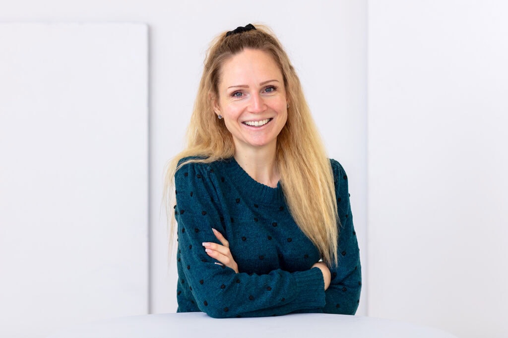 Cornelia Martinovic stands at a table with her arms folded and smiles into the camera
