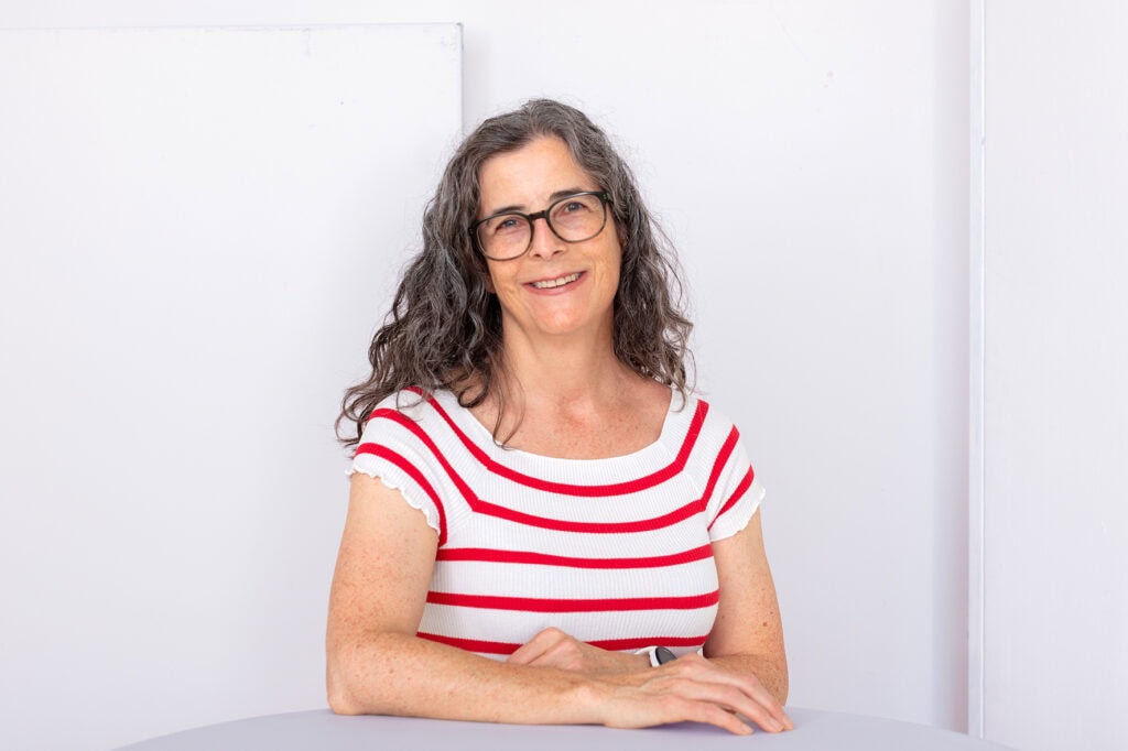 Nadine Pietzonka steht an einem Tisch und lächelt in die Kamera