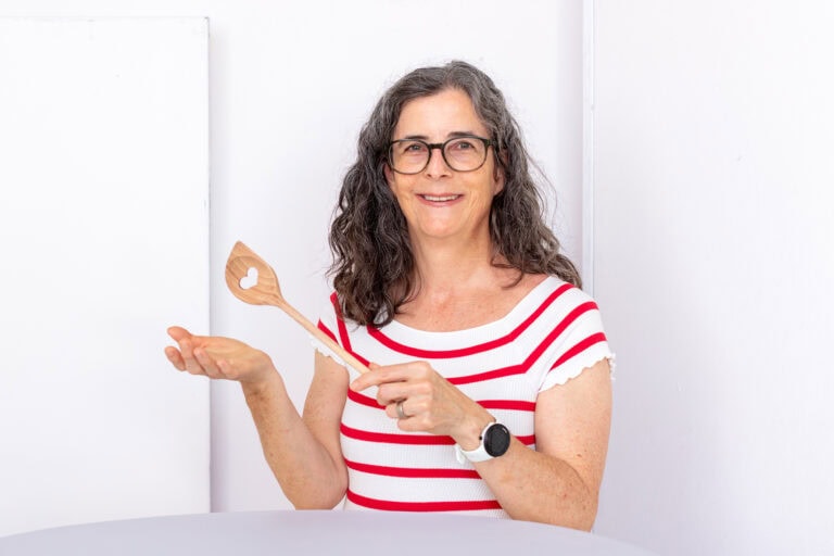 Nadine Pietzonka steht an einem Tisch, lächelt in die Kamera und präsentiert eine Holzkelle mit ausgeschnittenem Herz